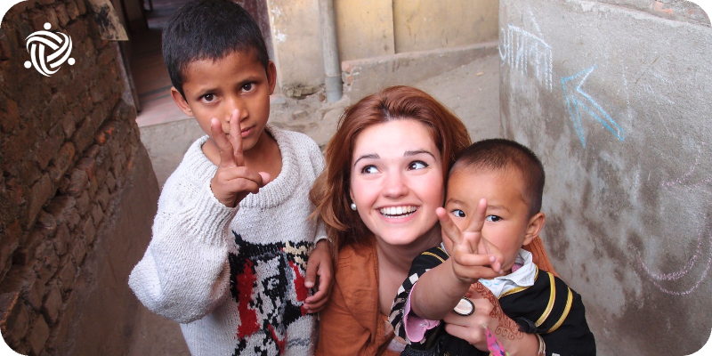 A young woman playing around with two children while volunteering in Childcare in Nepal.
